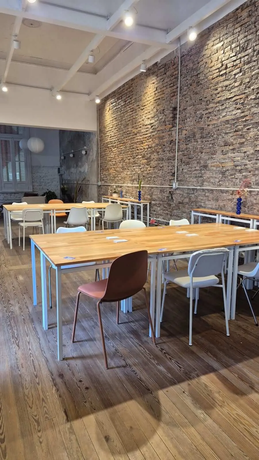 El salón de trabajo de La Casa, con mesas de madera y muro de ladrillo visto