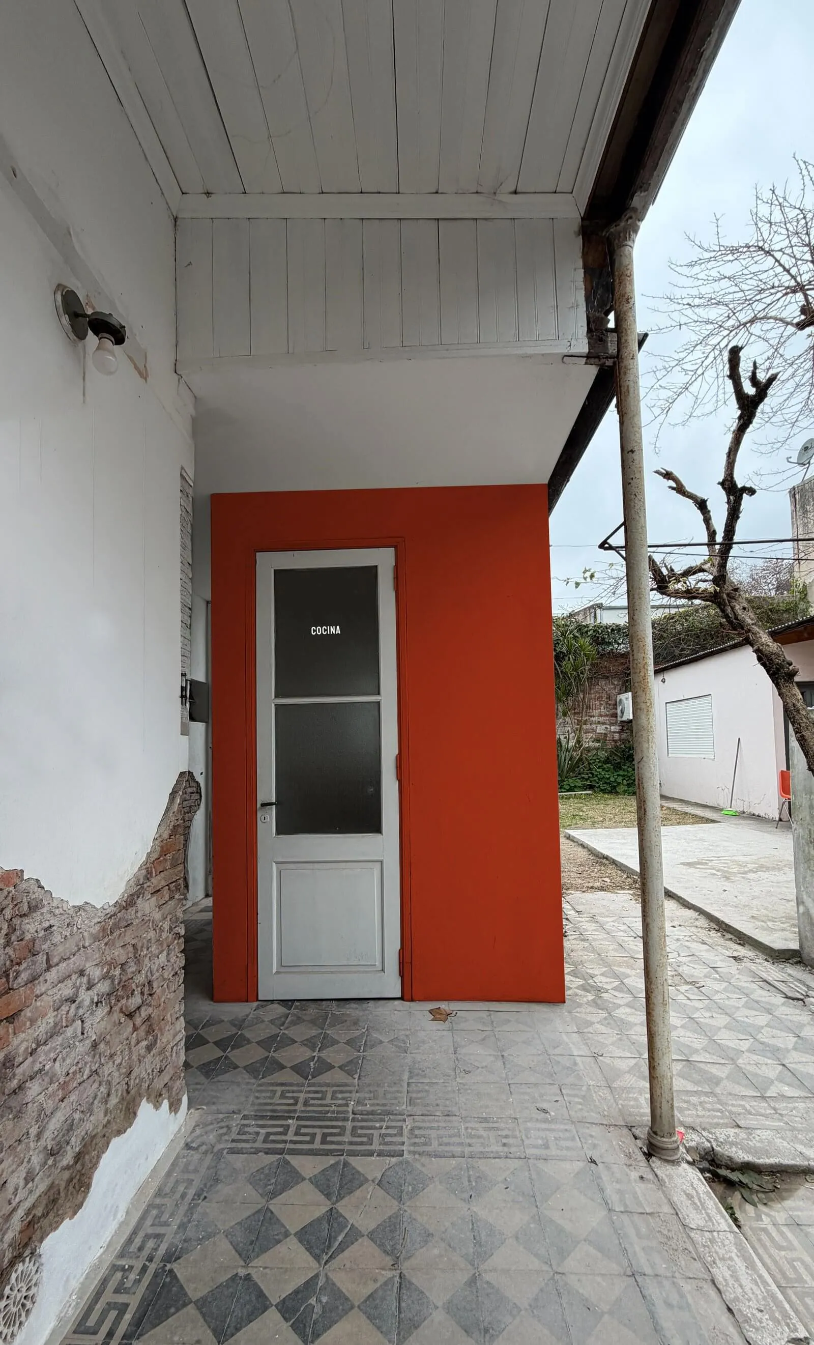 El patio de La Casa, con la puerta roja de la cocina y un árbol